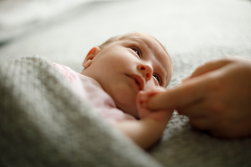 young baby holding a parent's finger