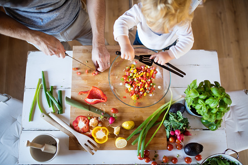 Little boy helping to make a meal with his Dad in the kitchen.