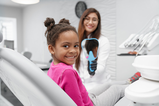 girl smiling while dentist shows a mirror