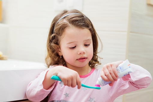 Child using toothpaste on her toothbrush.