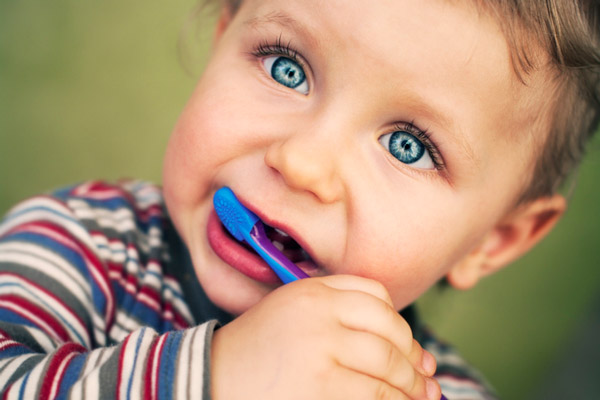 Portrait of toddler learning to brush his teeth.