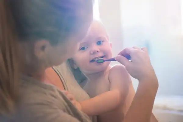 Baby chewing on teething ring and smiling before going to the dentist.