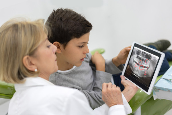 Young boy at the dentist looking at an x-ray on tablet computer