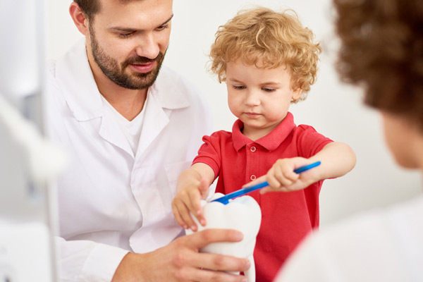  Toddler boy practicing brushing tooth with the dentist