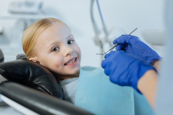 Blonde little girl smiling in dental chair.