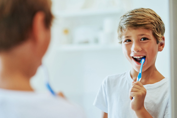 Young boy looking at mirror and brushing his teeth.