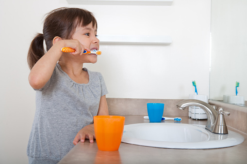 Adorable little girl brushing her teeth