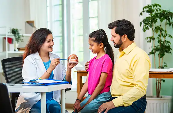 Little girl speaking with dentist next to her father